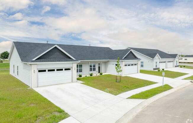 A white house with a grey roof and a driveway in front.