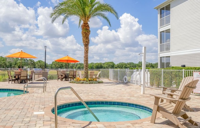 pool area with hot tub and chairs