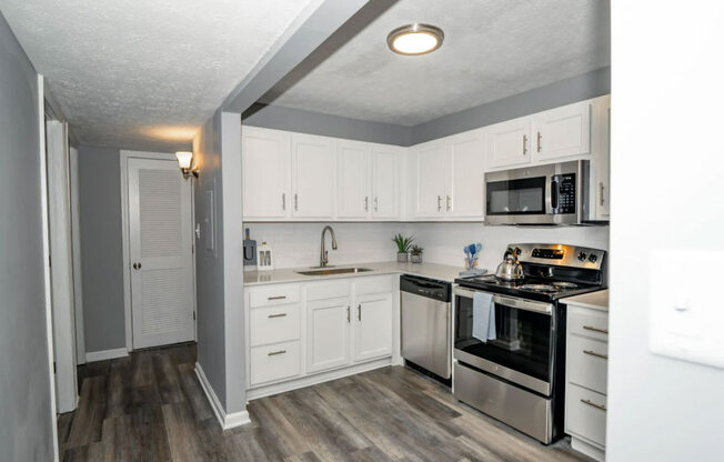 a kitchen with white cabinets and stainless steel appliances at Station JTown, Kentucky, 40299