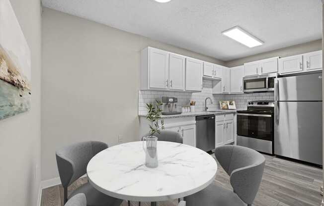 a kitchen with white cabinets and stainless steel appliances and a white marble table with four chairs