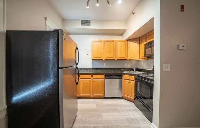 A kitchen with a black refrigerator and wooden cabinets.