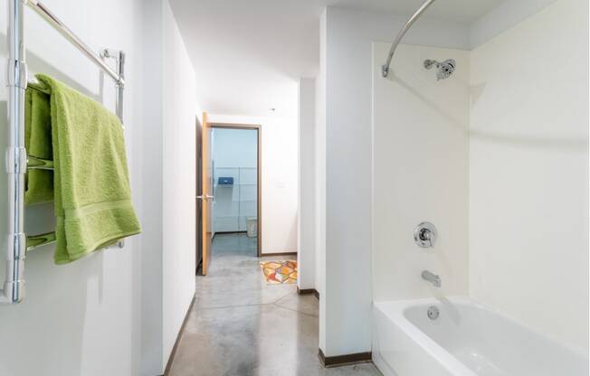 a bathroom with a white tub and a shower and a green towel