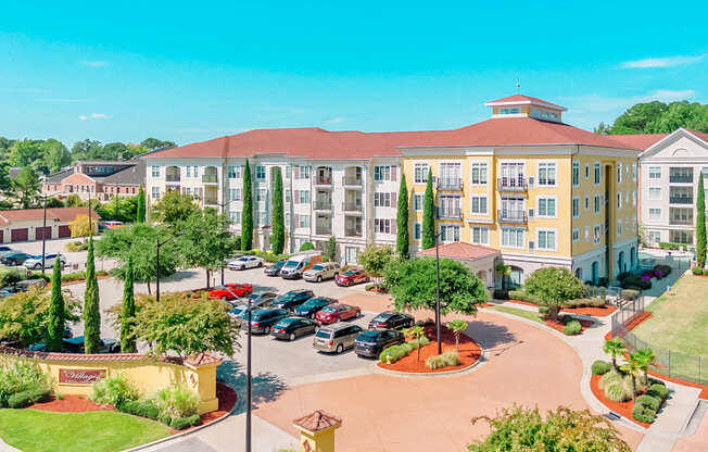 A large building with a red roof and a parking lot in front.