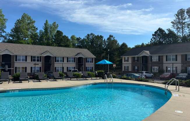 A swimming pool in front of a building with a blue umbrella.