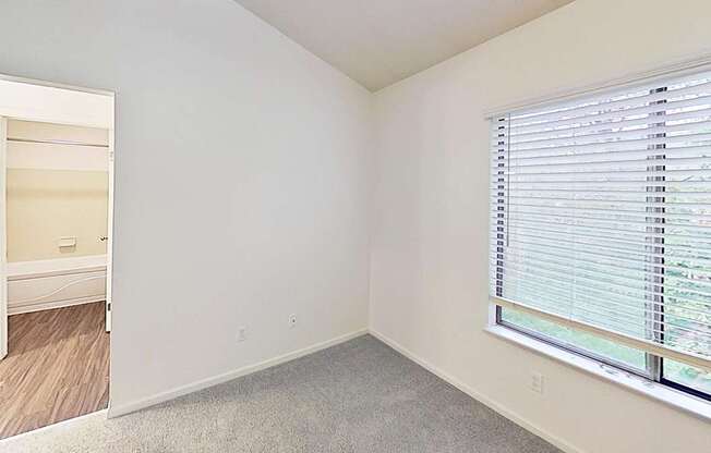 A master bedroom with a window covered by white blinds and an ensuite bathroom at Foxwood and The Hermitage, Portage, MI