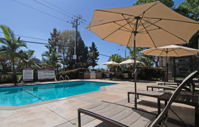 A pool area with a sun umbrella and a sign that says 
