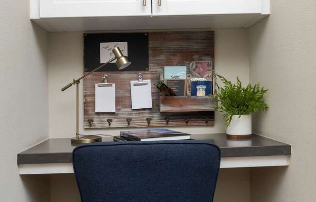 A blue chair sits in front of a desk with a laptop and a lamp.