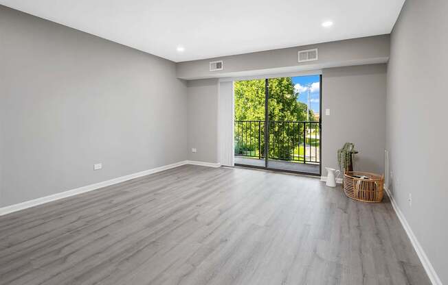 A room with a sliding glass door leading to a green outdoor area.