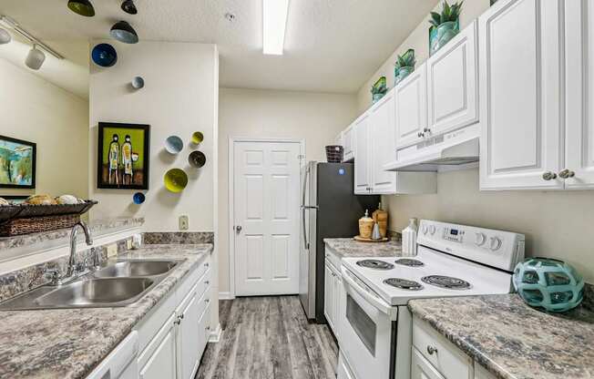 A kitchen with white cabinets and a black fridge.