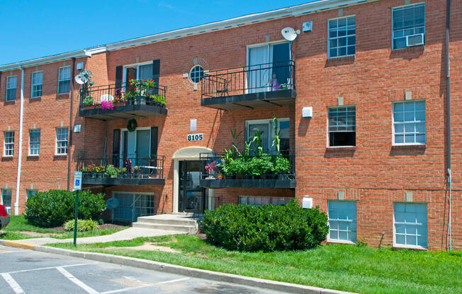 a red brick apartment building with balconies and grass