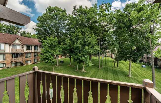 A balcony overlooks a grassy area with trees