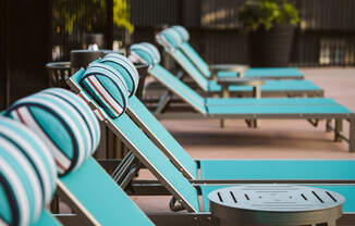 a row of blue chaise lounges with a table
