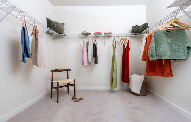 A room with clothes hanging on a rack and a chair.
