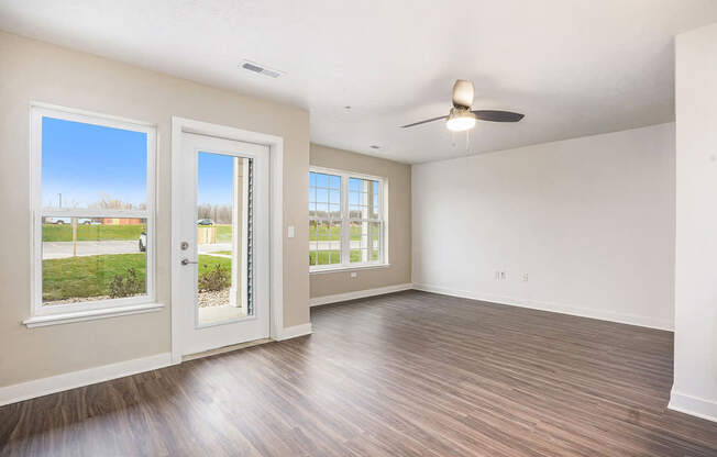 A living room with a ceiling fan and a french door to a private patio at Meadowbrooke Apartment Homes in Kentwood, MI 49512