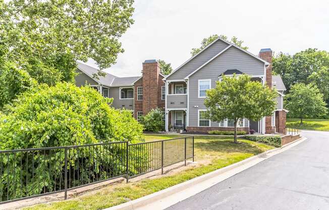 an empty street in front of a house with a fence