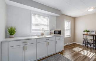 A kitchen with white cabinets and a microwave on the counter.