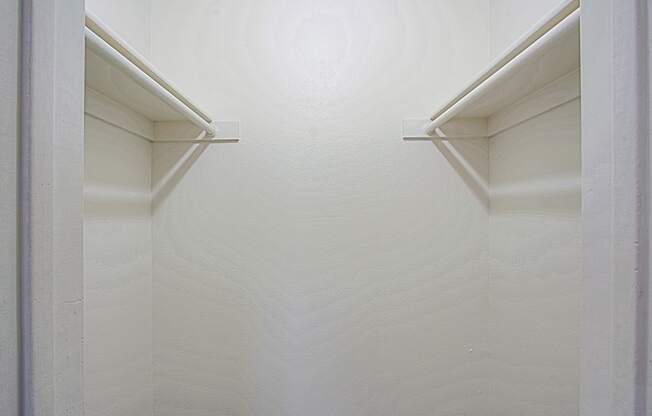 a closet with white walls and two white shelves