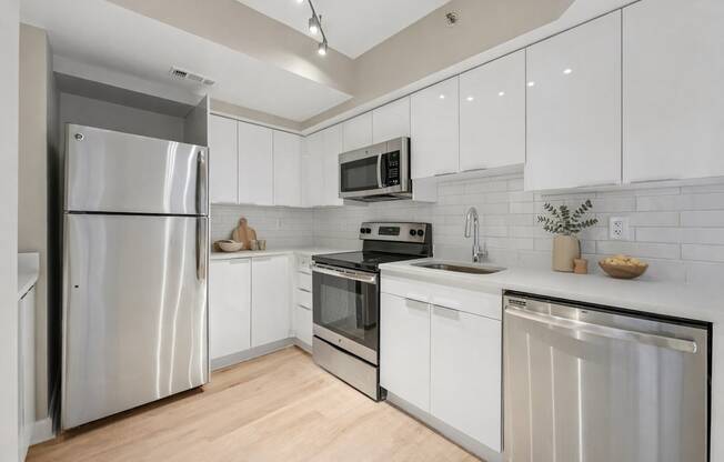 A modern kitchen with white cabinets and stainless steel appliances.