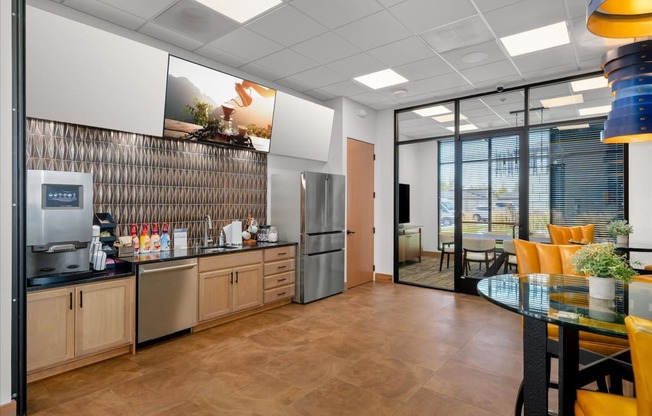 a kitchen and dining area in an office space with a table and chairs