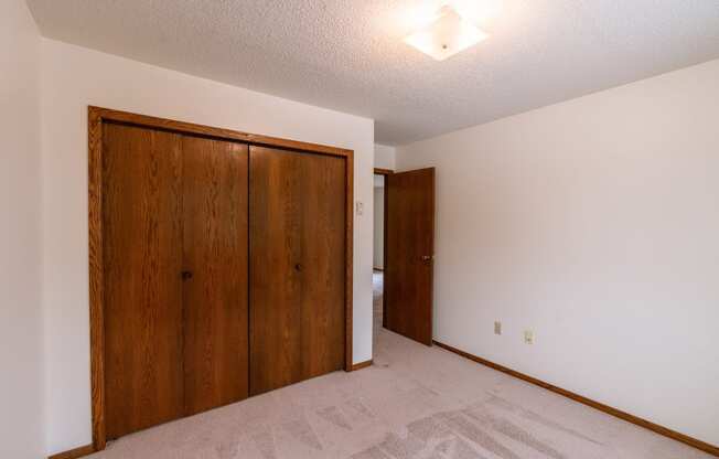 A bedroom with a closet. Fargo, ND Huntington Apartments.