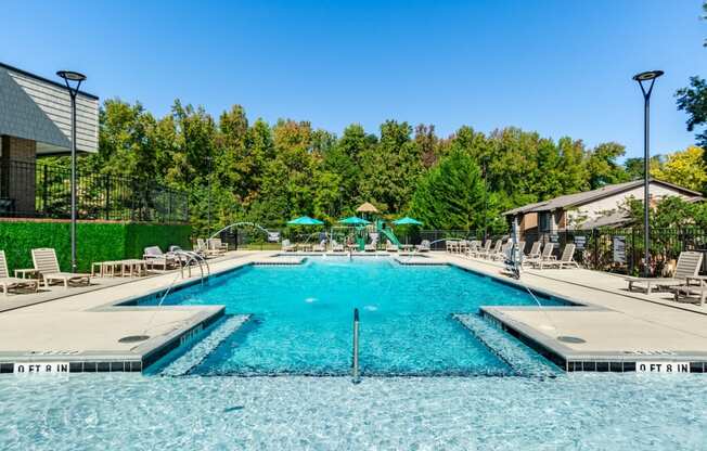 a swimming pool with chairs and umbrellas at the resort on a sunny day