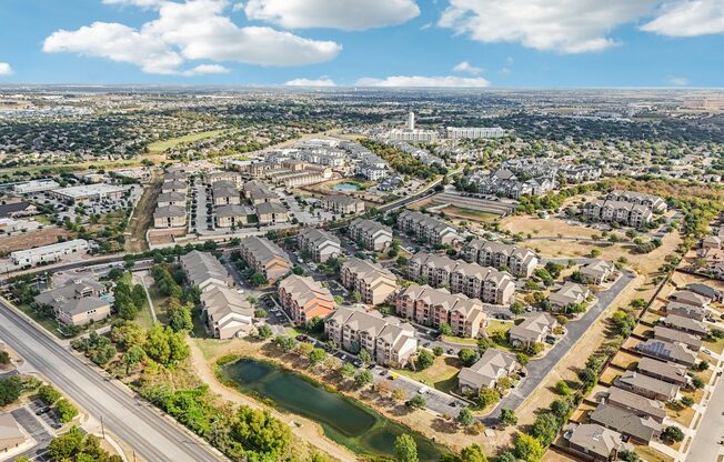 A bird's eye view of a residential area with apartment buildings, roads, and a body of water.