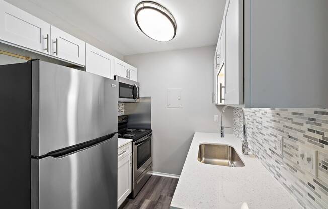 a kitchen with stainless steel appliances and white counter tops at Town & Country Apartments - Wixom, MI, Wixom, Michigan