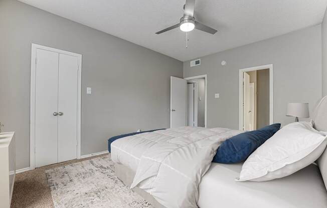 A bedroom with a bed, pillows, and a ceiling fan.