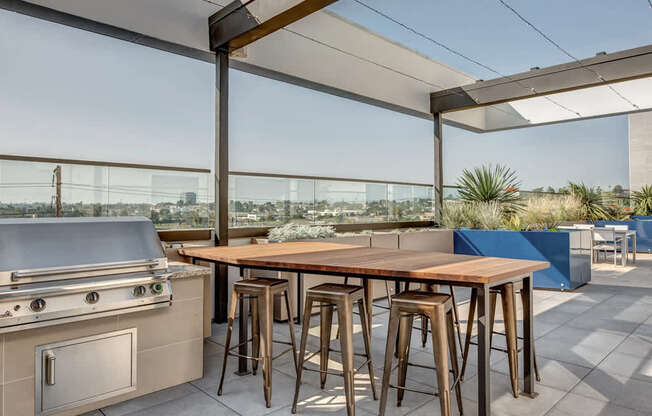 A modern outdoor kitchen with a grill and bar stools.