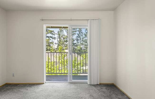 a bedroom with a sliding glass door and a balconyat Mill Pond Apartments, Auburn, WA 