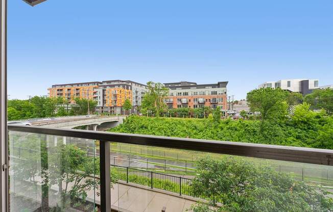 A balcony overlooks a green park and buildings.