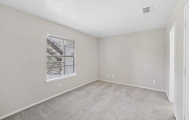 A room with a window and carpeted floor.
