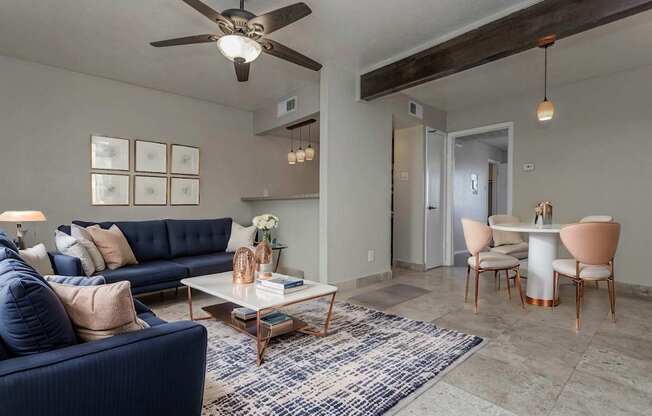 A living room with a blue sofa, a coffee table, and a ceiling fan.