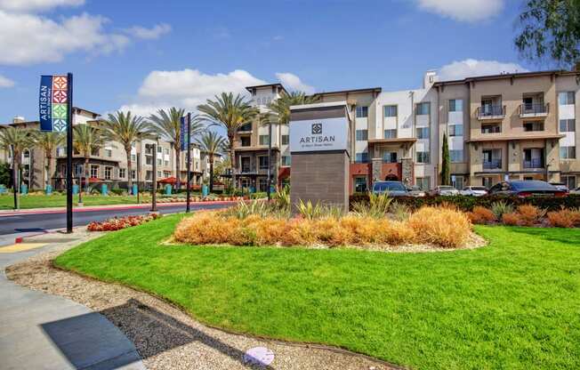 an apartment complex with a sign in the middle of a grassy area