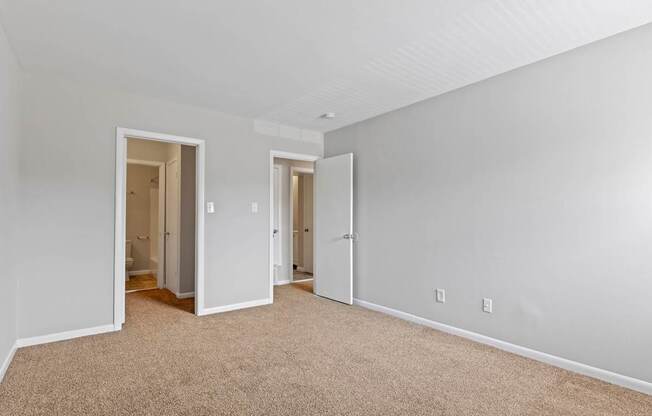 a bedroom with white walls and carpet and a door to a hallway