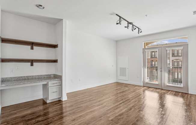 an empty living room with white walls and a door to a balcony