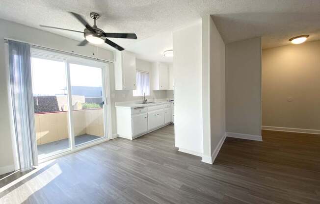 an empty living room and kitchen with a ceiling fan