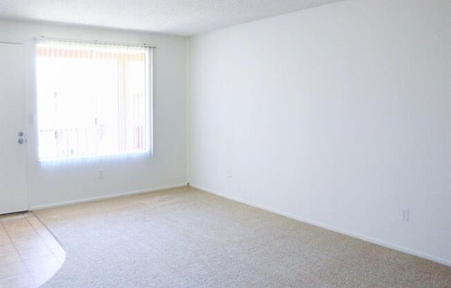 an empty room with a large window and white walls