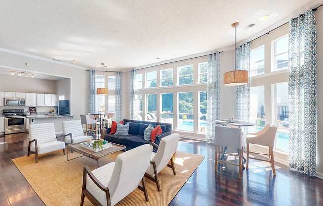 a living room with a couch and chairs and a kitchen with a large window