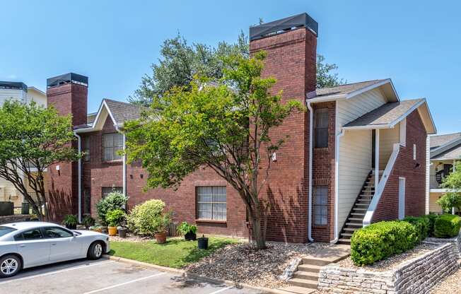 A house with a red brick exterior and a white car parked in front.