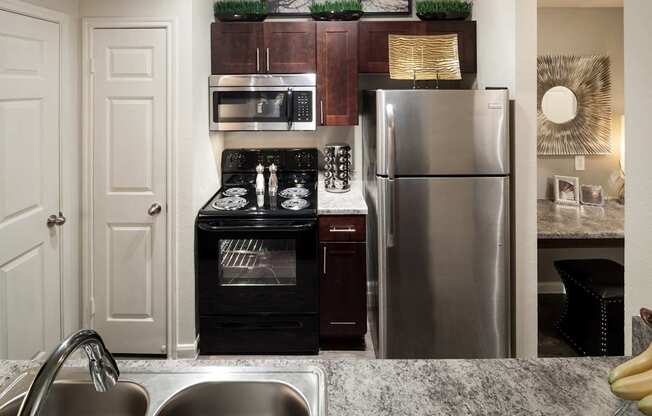 A modern kitchen with a stainless steel refrigerator, oven, and sink.