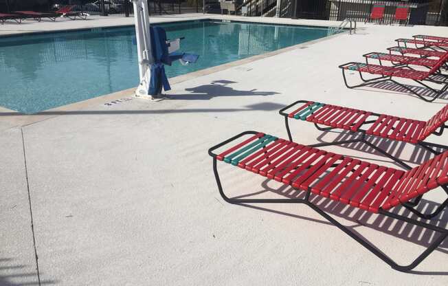 Row of red  chairs next to a swimming pool at River Crossing Apartments, Thunderbolt, GA, 31404