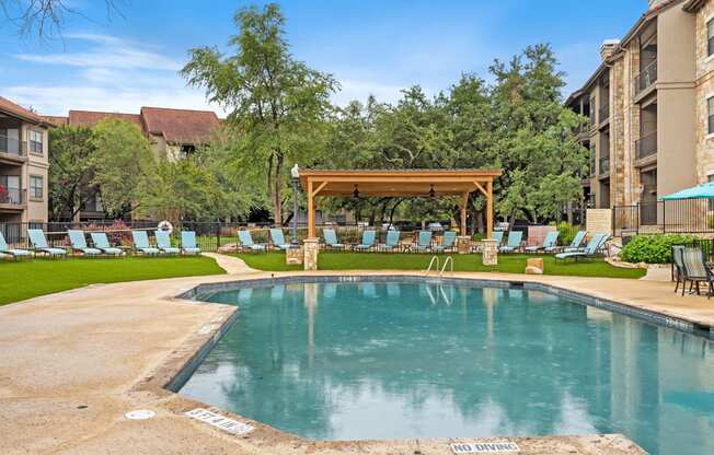a resort style pool with chaise lounge chairs and a gazebo