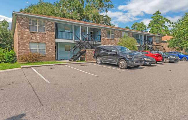 a parking lot in front of an apartment building with cars parked in front