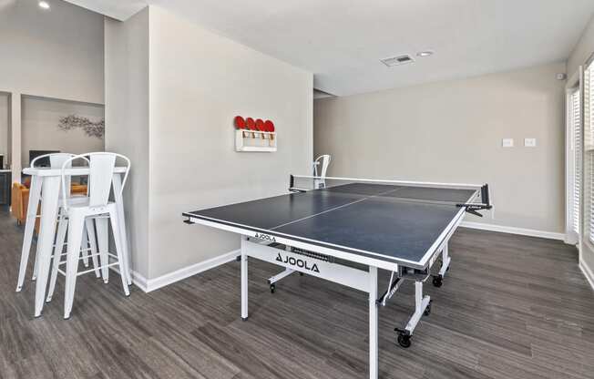 a games room with a ping pong table and chairs