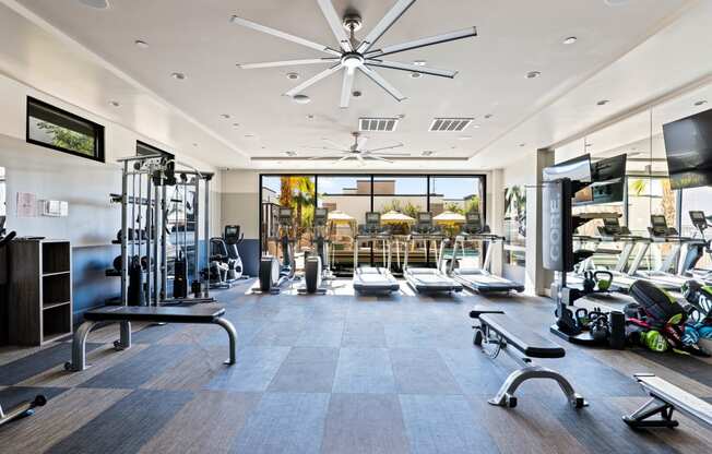 a gym with weights and cardio equipment and a large window