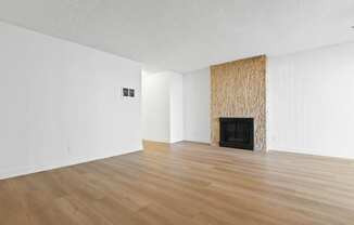 an empty living room with a fireplace and wooden floors