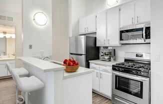 an apartment kitchen with stainless steel appliances and white cabinets