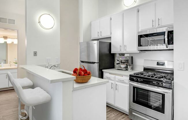 an apartment kitchen with stainless steel appliances and white cabinets