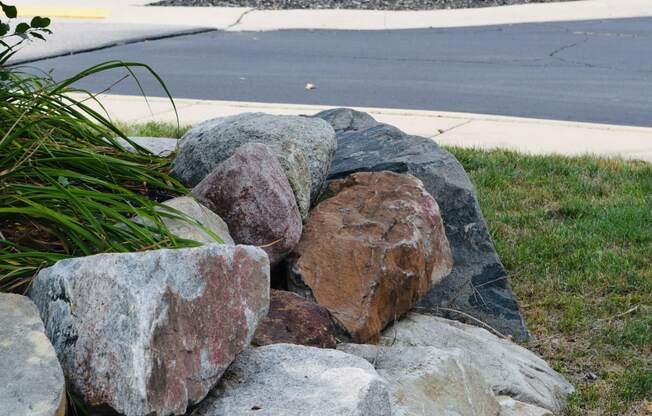 a pile of rocks sitting in the grass in front of a sign